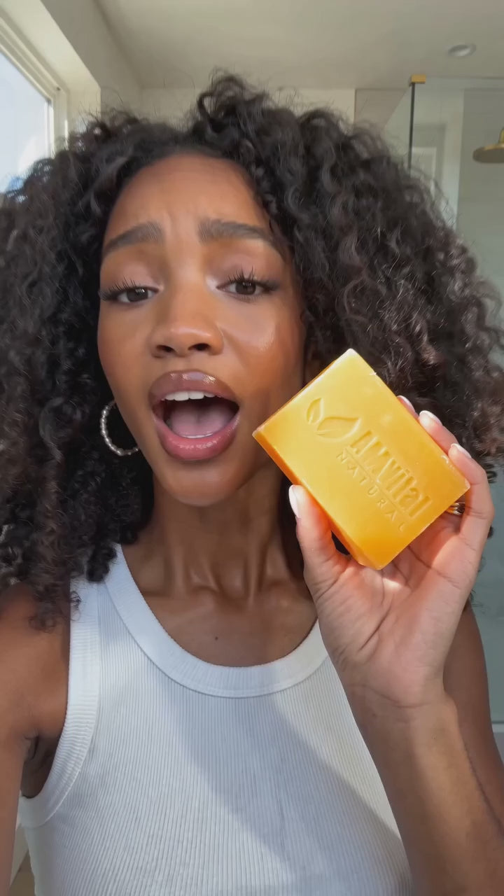 Woman explaining how AMVital turmeric kojic acid soap fades dark spots and brightens skin in one cleansing step