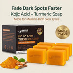 AMVital Natural Kojic Acid Turmeric Soap shown with its black retail box, several orange-yellow soap bars, a small pile of orange turmeric powder, and turmeric roots on a light beige background. Large marketing text at the top reads 'Fade Dark Spots Faster' and 'Kojic Acid + Turmeric Soap' with 'Made for Melanin-Rich Skin Types.