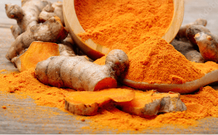 Turmeric powder and fresh turmeric on wooden background.