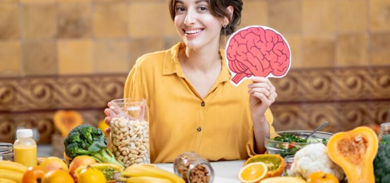 A woman holding up a drawing of a brain surrounded by brain health foods.