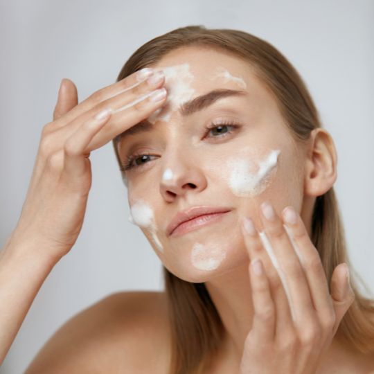 Turmeric-based foam cleanser being used on a face.