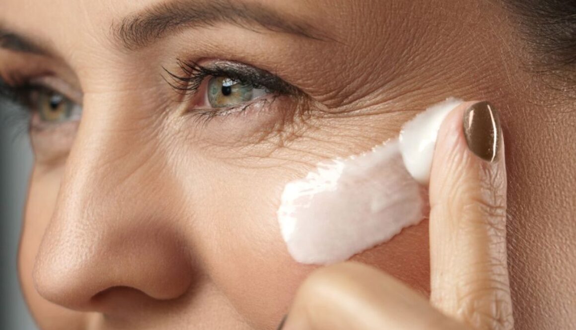 The woman applies cream to her face to remove wrinkles.