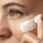 The woman applies cream to her face to remove wrinkles.