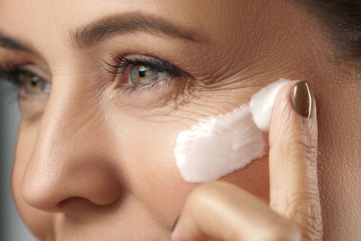 The woman applies cream to her face to remove wrinkles.