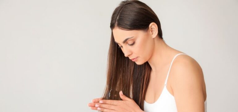 The woman applies organic hair oil to her hair.