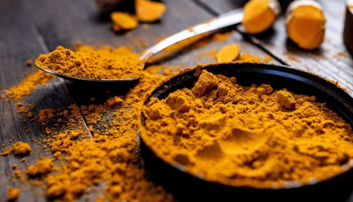 A bowl of turmeric spreads out on a table.