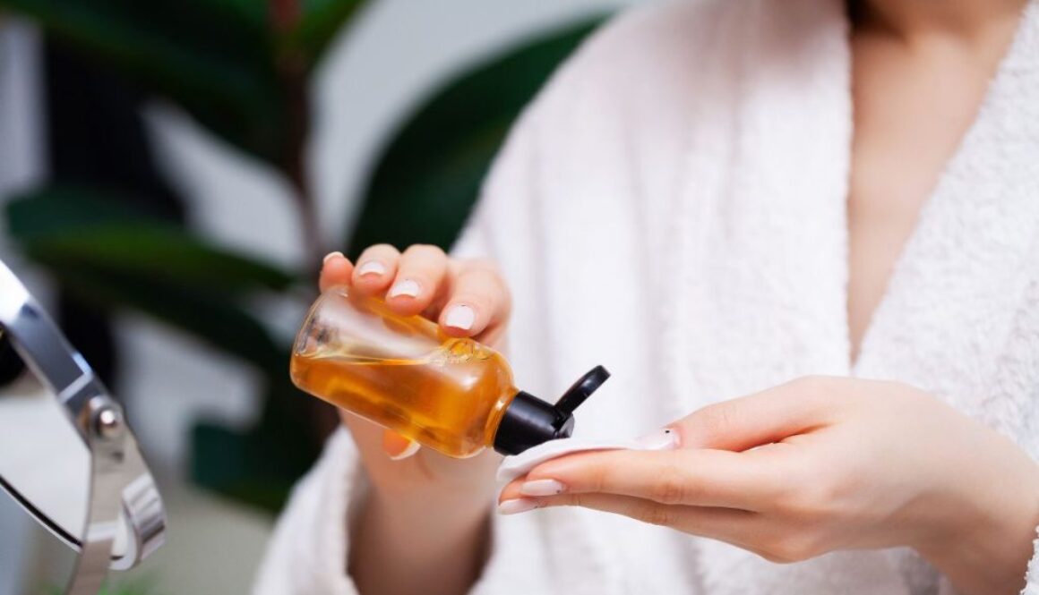 The woman applies turmeric toner to a cotton ball.