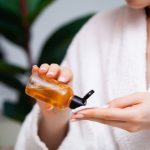 The woman applies turmeric toner to a cotton ball.