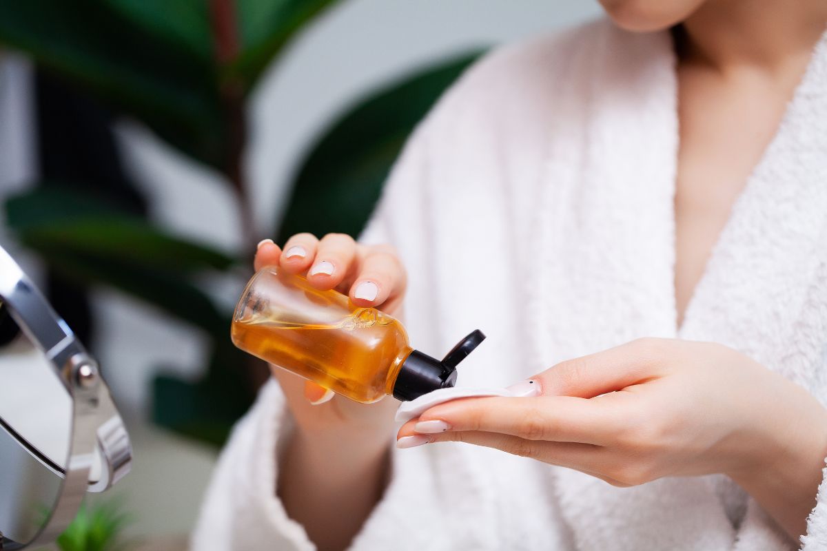 The woman applies turmeric toner to a cotton ball.