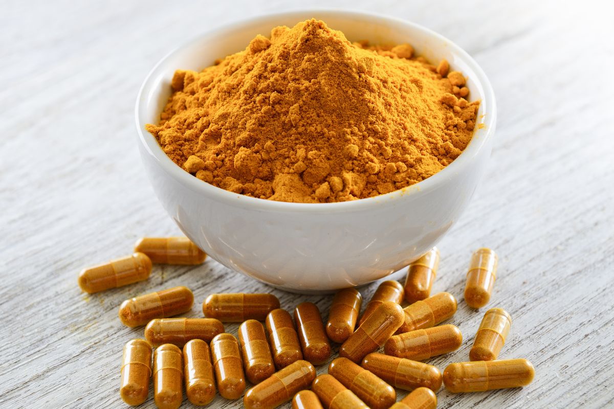 A bowl of turmeric and supplements.