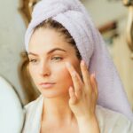 A woman applies turmeric skincare to her face.